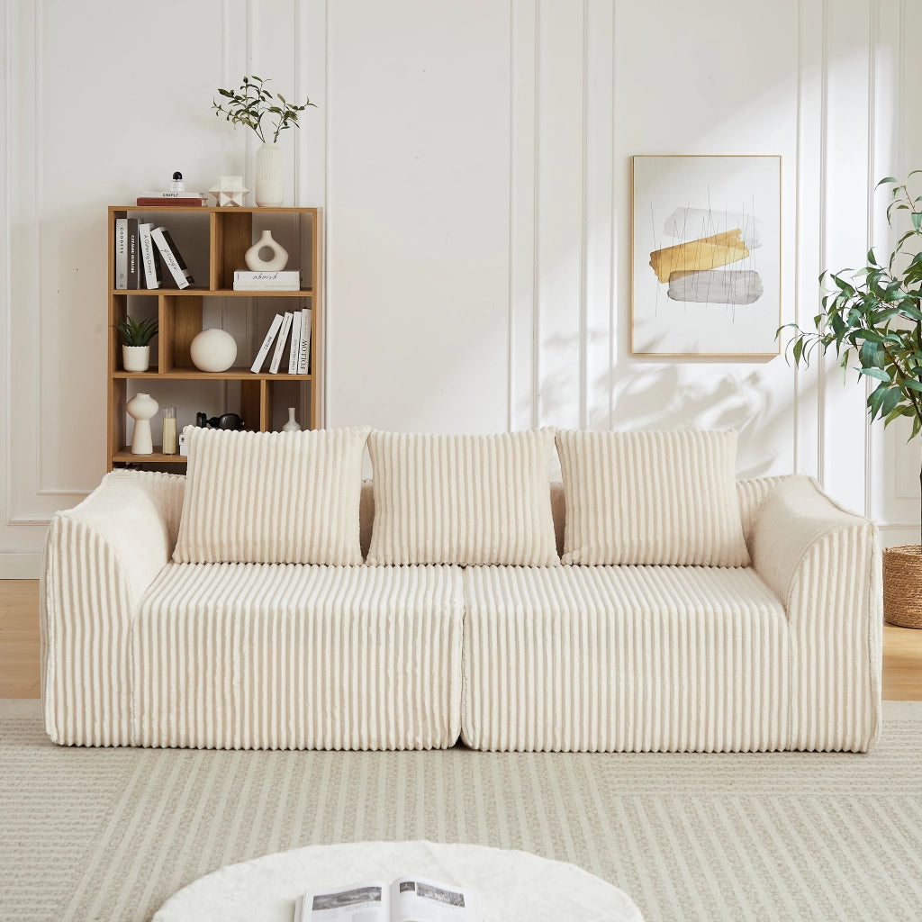 Divano modulare con schienale e braccioli curvi, seduta ampia e due cuscini in velluto a coste beige