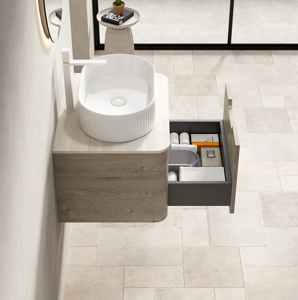 Mobile bagno sospeso 60 cm con lavabo ovale bianco in ceramica, piano in travertino sinterizzato e armadietto in compensato con cassetto, finitura rovere crema, preassemblato