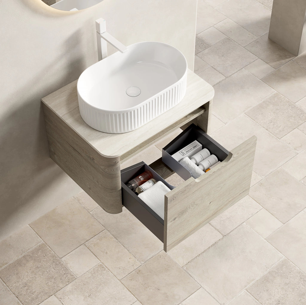 Mobile bagno sospeso 60 cm con lavabo ovale bianco in ceramica, piano in travertino sinterizzato e armadietto in compensato con cassetto, finitura rovere crema, preassemblato