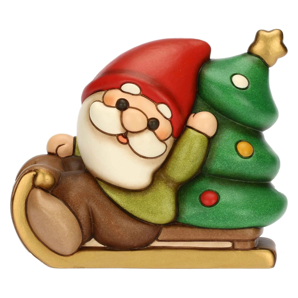 Figura natalizia di un gnomo di nome Oliver, raffigurato su una slitta, realizzata in Vetroceramica, dimensioni 13,6 x 10,3 x 18,8 cm