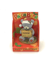 Orso di Natale con cappello e spilla con la scritta "ABBI MERRY XMAS"