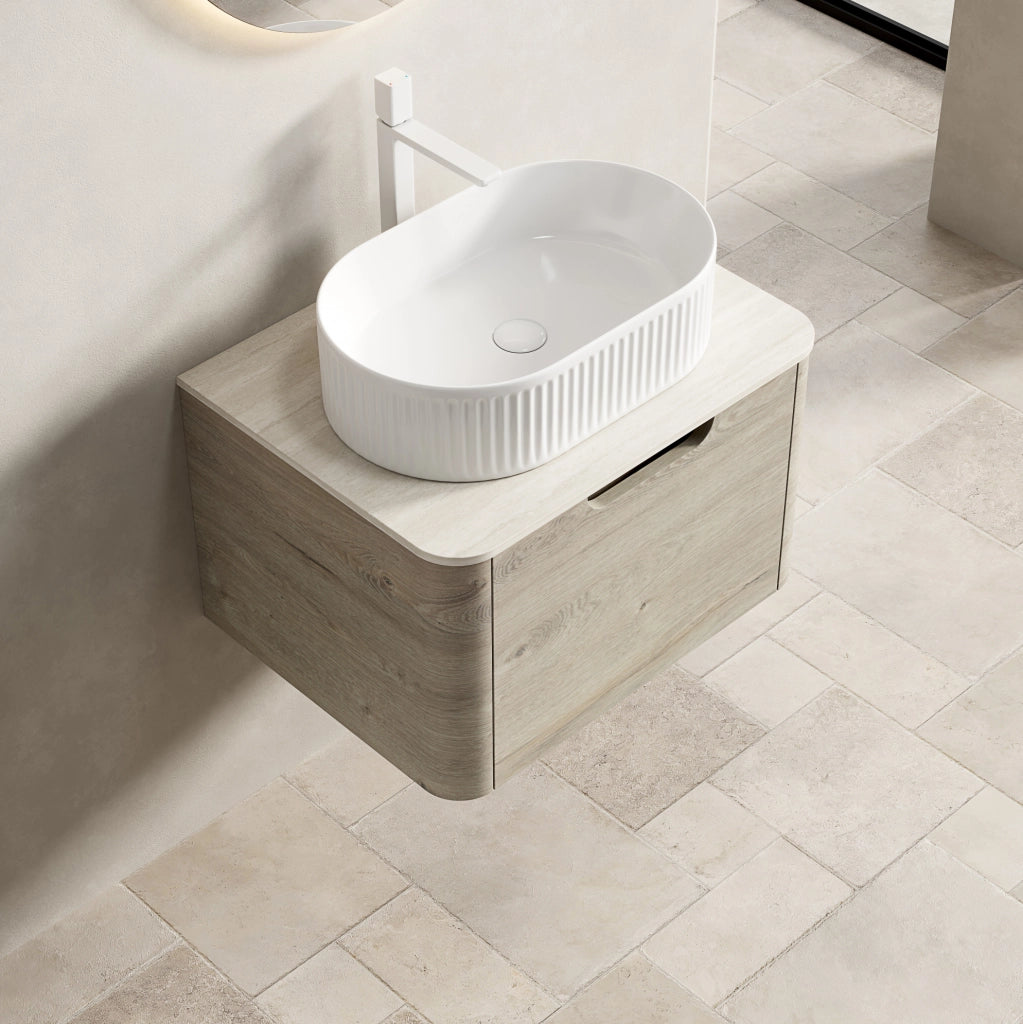 Mobile bagno sospeso 60 cm con lavabo ovale bianco in ceramica, piano in travertino sinterizzato e armadietto in compensato con cassetto, finitura rovere crema, preassemblato